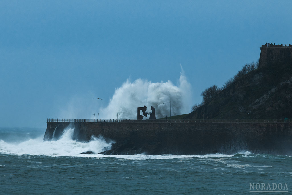 Olas rompiendo en el Paseo Nuevo junto a la escultura ‘Construcción Vacía’ de Oteiza